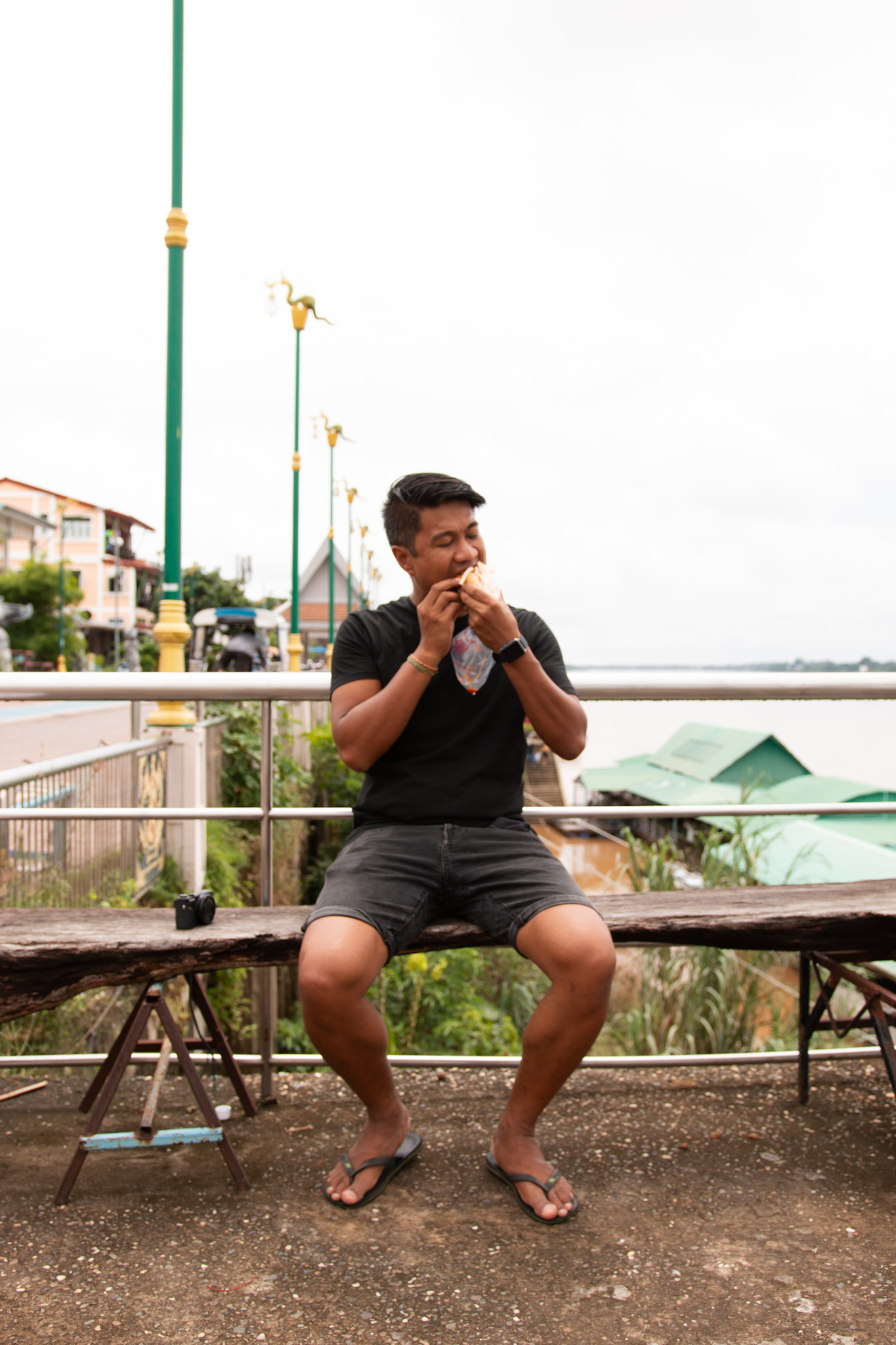 Weeri eating Banh Mi besides the Mekong River